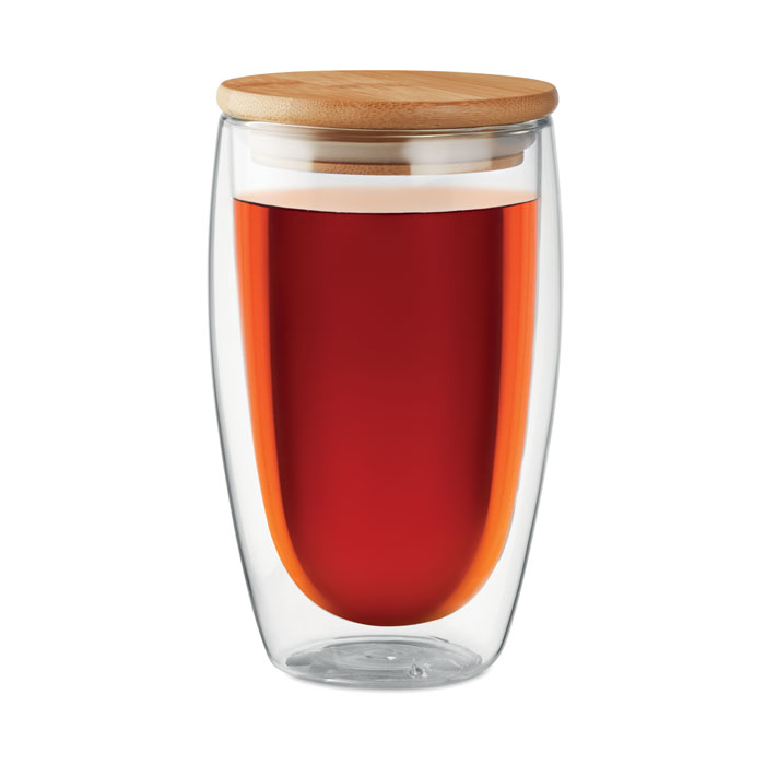 Vaso de vidrio de doble pared con tapa de bambú lleno de té rojo.
