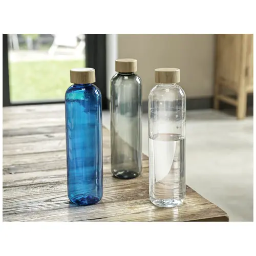 botellas de agua de cristal de colores sobre mesa de madera junto a ventana